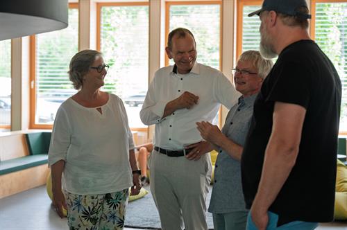 HSD-Präsidentin Edeltraud Vomberg und TH-OWL-Präsident Prof. Dr. Jürgen Krahl stehen mit zwei weiteren Männern in einem hellen Raum zusammen und unterhalten sich lachend.